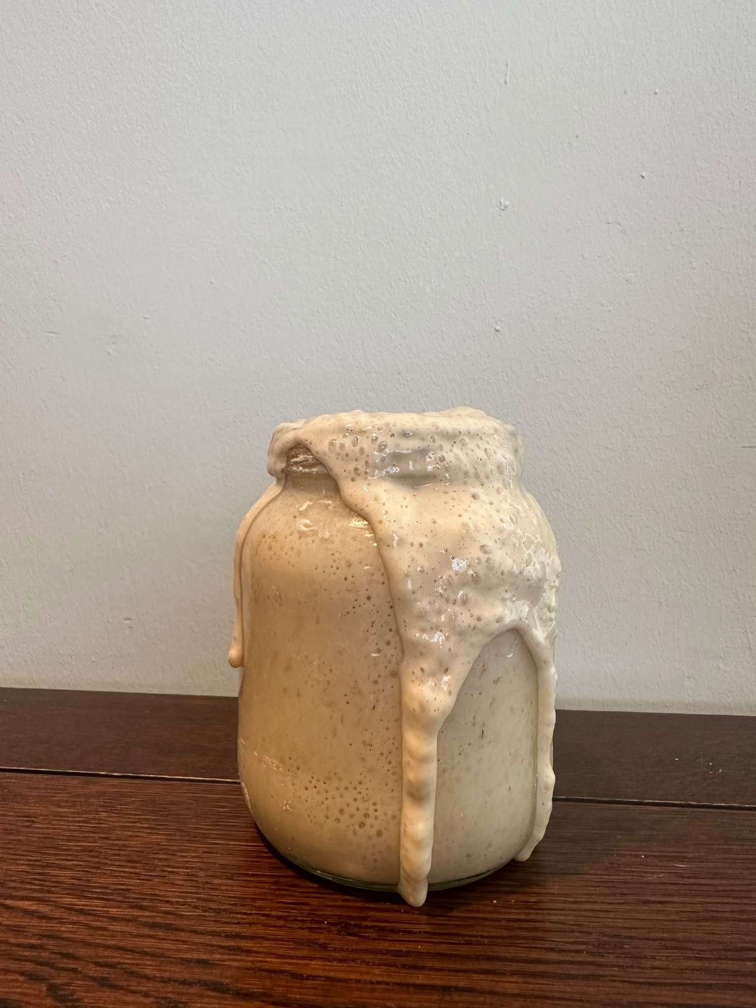 De zelfgekweekte zuurdesemstarter, zo actief dat hij over de rand van de glazen pot bruist